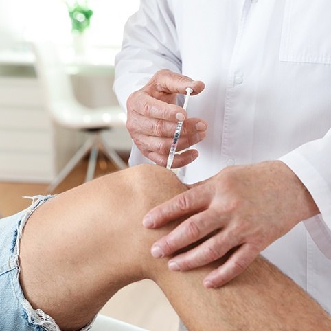 Doctor administering injection in knee