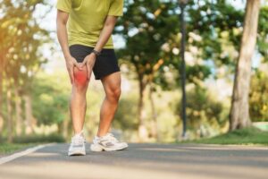 Man experiencing knee pain while walking outdoors